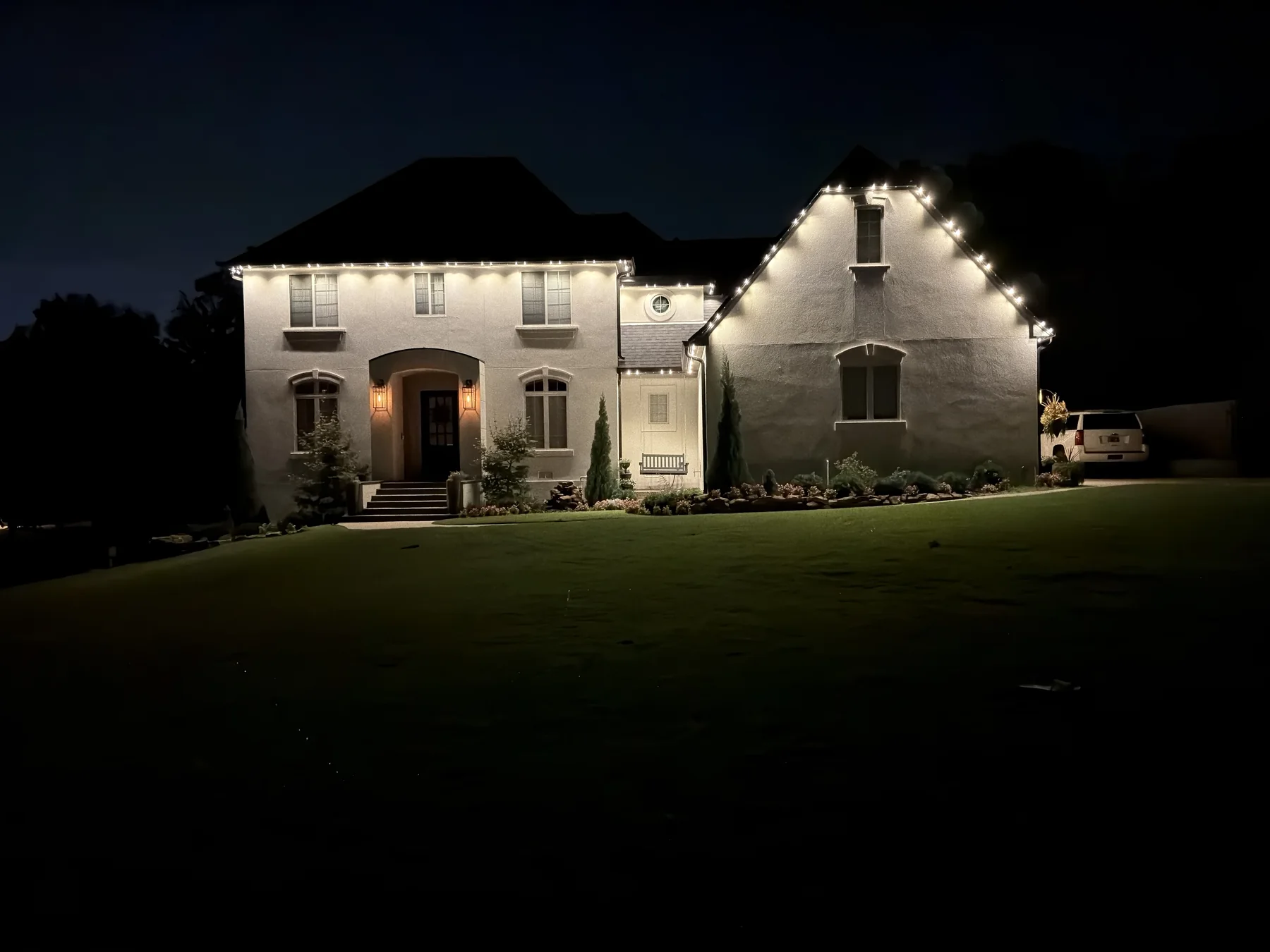 Completed permanent lighting installation glowing warm white across the roofline